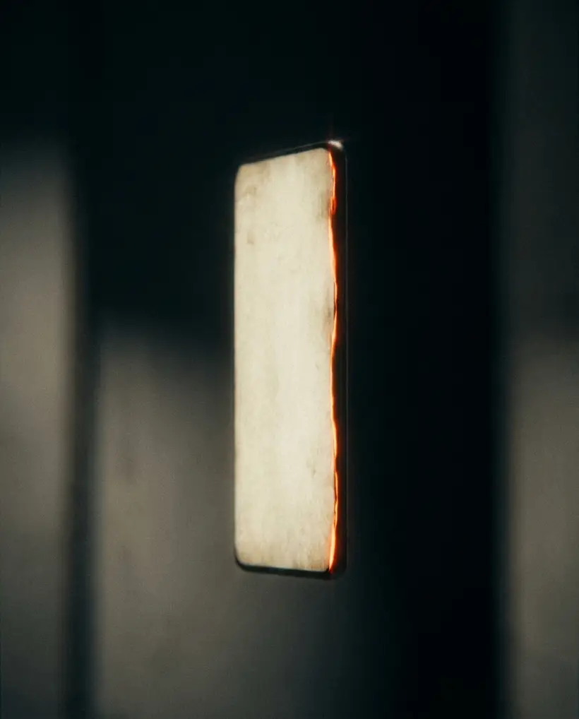A tall sliver of glowing light standing alone in darkness, rimmed in warm orange.
